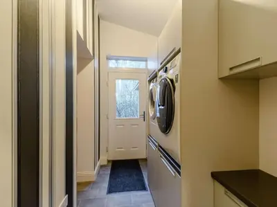 a kitchen with a washer and dryer next to a door at Luxury Guest House Getaway for 2 in Drymen