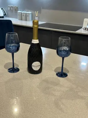 a bottle of wine and two glasses on a table at Cameron Coach House Modern Property in Murrayfield Edinburgh in Edinburgh