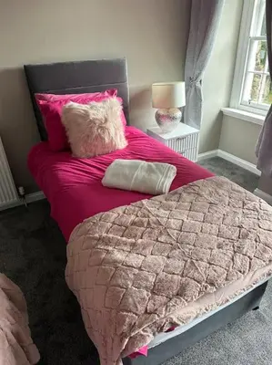 a bed with a pink blanket and pillows on it at Cameron Coach House Modern Property in Murrayfield Edinburgh in Edinburgh