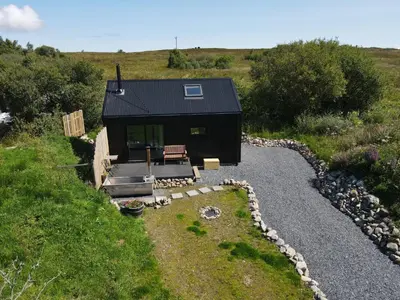 a tiny house on a hill with a gravel driveway at Jura - The Black Hut in Isle of Jura