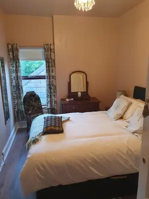 a bedroom with a bed and a mirror and a window at The Villa Farmhouse in Cushendun