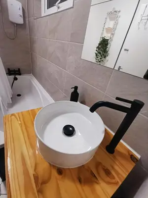 a bathroom with a white sink on a wooden cutting board at Peaceful house in the heart of Glasgow city, close to Queen Elizabeth Hospital and Govan subway, Free Private Parking in Glasgow