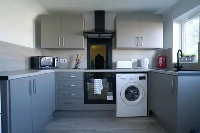 a kitchen with a washing machine and a microwave at McCracken House in Uddingston