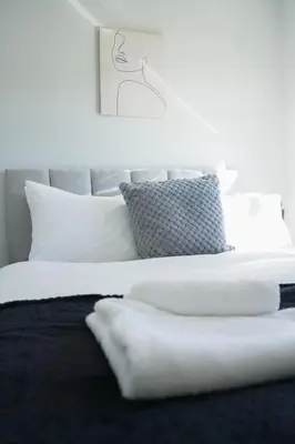 a bed with white sheets and pillows in a bedroom at McCracken House in Uddingston