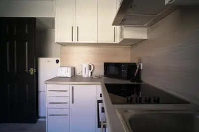 a small kitchen with white cabinets and a microwave at Sauchie House in Sauchie