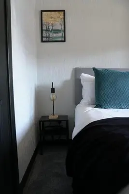 a bedroom with a bed with a blue pillow and a table at Sauchie House in Sauchie