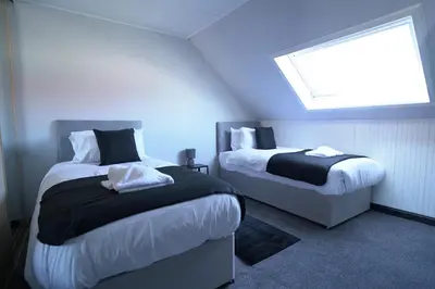 a bedroom with two beds and a window at Sauchie House in Sauchie