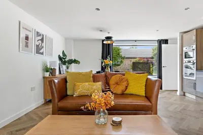 a living room with a brown leather couch with yellow pillows at Peterswell Holiday Cottage in Houston