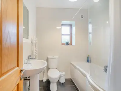 a white bathroom with a sink and a toilet and a tub at South Steading in West Kilbride