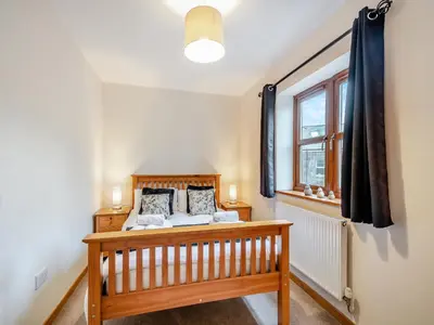 a bedroom with a wooden bed and a window at South Steading in West Kilbride