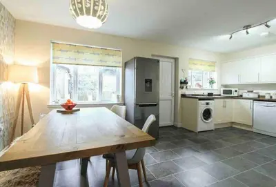 a kitchen with a dining room table and a kitchen with a refrigerator at Beautiful cosy 2-bedroom entire house in Connel, near Oban in Connel
