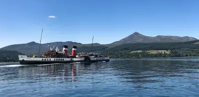 a large boat on the water with people on it at The Arran Lodge & Arran Sleep Huts in Lamlash