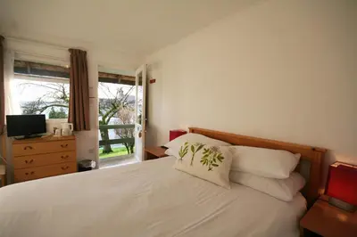 a bedroom with a white bed and a window at The Arran Lodge & Arran Sleep Huts in Lamlash