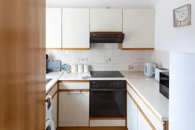 a kitchen with white cabinets and a black oven at Executive Apartment By Inverkeithing Train Station in Fife