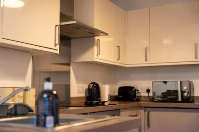 a kitchen with white cabinets and a sink at Dalwhinnie Apartment in Oban