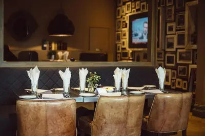 a dining table with chairs and a television in a restaurant at Murrayfield Hotel in Edinburgh