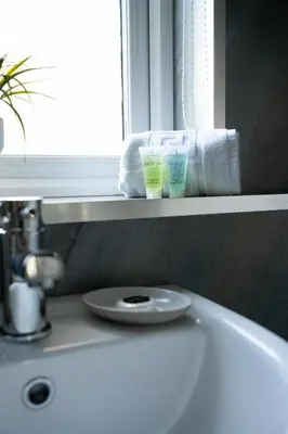 a bathroom sink with two cups on a window ledge at 2 BDR Apt By Caledonia Luxe Stays Short Lets & Serviced Accommodation Airdrie in Airdrie