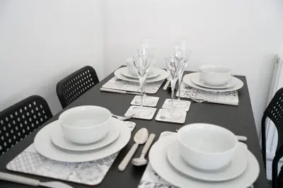 a black table with white dishes and wine glasses at 2 BDR Apt By Caledonia Luxe Stays Short Lets & Serviced Accommodation Airdrie in Airdrie