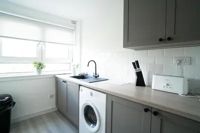 a kitchen with a washing machine and a sink at 2 BDR Apt By Caledonia Luxe Stays Short Lets & Serviced Accommodation Airdrie in Airdrie