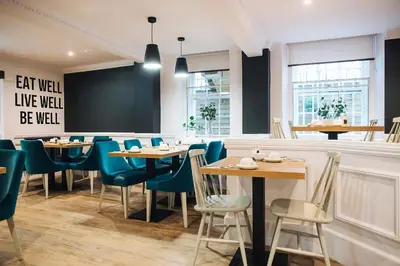 a restaurant with wooden tables and blue chairs at Argyll Hotel in Glasgow