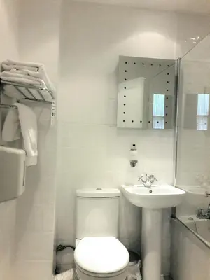 a white bathroom with a toilet and a sink at Argyll Hotel in Glasgow