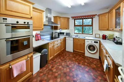 a kitchen with wooden cabinets and a washer and dryer at North Blairkip Eildon in Sorn