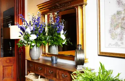 a vase of flowers on a dresser in front of a mirror at The Roseate Edinburgh - Small Luxury Hotels of the World in Edinburgh