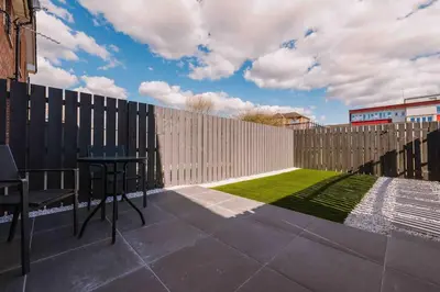 a patio with a fence and a table and grass at SleepLuxury ApartHOUSE in Glasgow