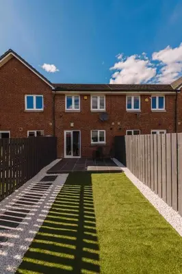 a brick house with a fence and a grass yard at SleepLuxury ApartHOUSE in Glasgow