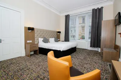 a hotel room with a bed and a chair at Albion Hotel in Glasgow