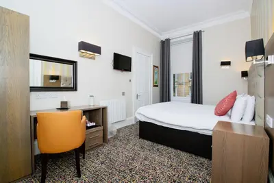 a hotel room with a bed and a desk and a chair at Albion Hotel in Glasgow