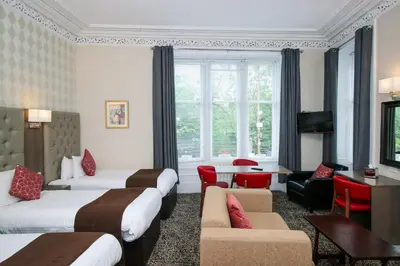 a hotel room with two beds and a table and chairs at Albion Hotel in Glasgow