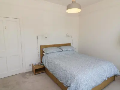 a bedroom with a bed with a blue comforter at 6 Kirkstyle in Biggar