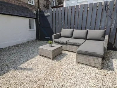 a patio with two wicker chairs and a couch at 6 Kirkstyle in Biggar