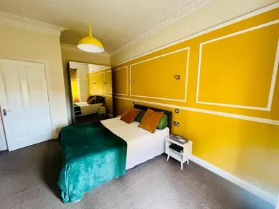 a bedroom with a large bed with yellow walls at CAMPBELL 100 DUNFERMLINE in Fife