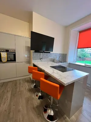a kitchen with a counter with orange bar stools at CAMPBELL 100 DUNFERMLINE in Fife