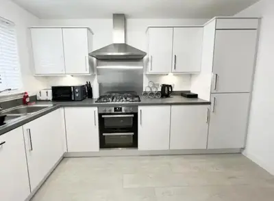 a kitchen with white cabinets and a stove top oven at Superb 3 Bed Home Away from Home in Glasgow, just off M8 with free parking in Steps