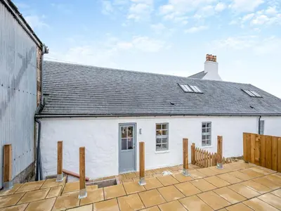 a white house with a roof and a wooden deck at The Byre - Uk45343 in Ayr