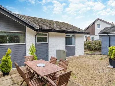 a backyard with a wooden table and chairs at Crarae in Corrie