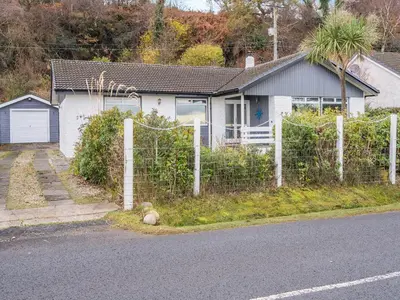 a white fence in front of a house at Crarae in Corrie
