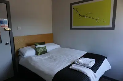 a small bed in a room with a green picture at Boreland Lodge Hotel in Inverkeithing