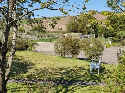 a blue chair sitting in the middle of a yard at Ash Cottage in Stranraer