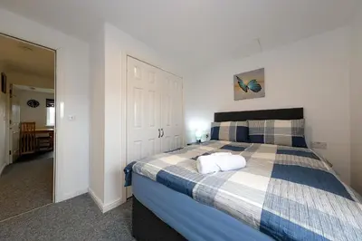 a bedroom with a bed with a blue and white blanket at Prime Duloch 2nd Floor Apartment by TBA in Fife