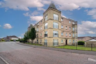 a large brick building on the side of a street at Prime Duloch 2nd Floor Apartment by TBA in Fife