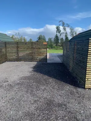 a wooden fence with a gate and a driveway at Tawny Owl Pod with Hot Tub in Oban