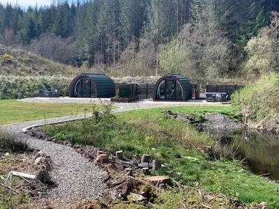 two green domes in a field next to a river at Tawny Owl Pod with Hot Tub in Oban