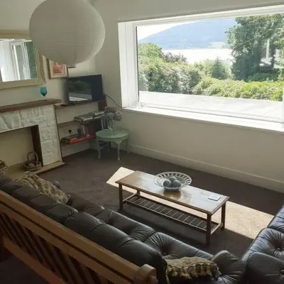 a living room with a couch and a large window at Peaceful and Stunning Waterside Location in Helensburgh