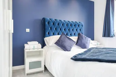 a blue bedroom with a bed with a blue headboard at Doralan in Bishopbriggs