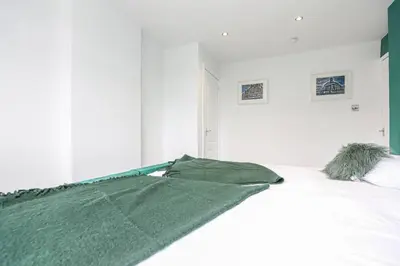 a white bed with a green blanket on it at Doralan in Bishopbriggs