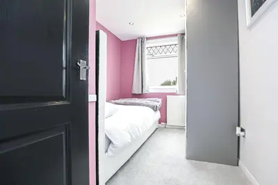 a bedroom with pink walls and a door with a bed at Doralan in Bishopbriggs